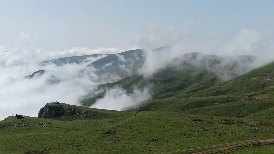 Green ridge of Mount Dimats rising above cloud in the valleys